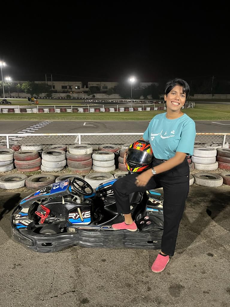 Mehak posing with a go-kart and helmet at a race track